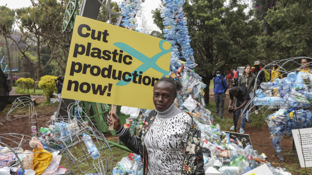 A protestor stands near a pile of plastic bottles in a march to demand the drastic reduction in global plastic production ahead of INC-3, in the streets of Nairobi, Kenya, 11 November 2023